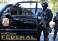 Operação da Polícia Federal com agentes armados em veículo oficial.