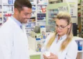 Profissionais analisando medicamento em farmácia moderna.