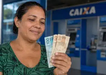 Mulher observa cédulas de real em frente a uma agência da Caixa, representando os pagamentos do Bolsa Família entre os dias 22 e 24 de julho.