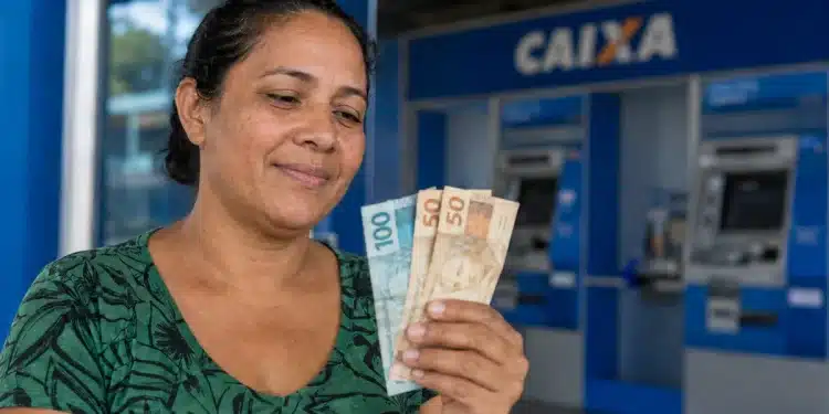 Mulher observa cédulas de real em frente a uma agência da Caixa, representando os pagamentos do Bolsa Família entre os dias 22 e 24 de julho.