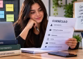 Imagem ilustrativa de jovem estudante segurando uma folha com as seções de dados pessoais, formação acadêmica, habilidades, cursos e experiências enquanto revisa o currículo para estágio