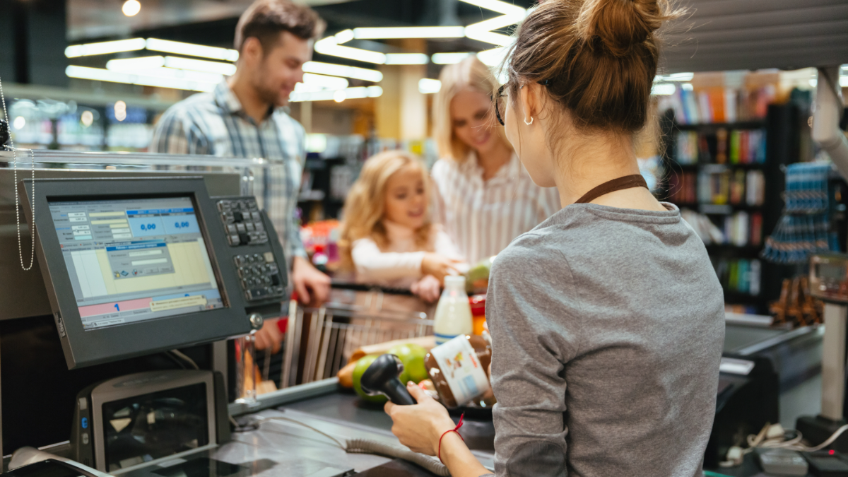 Operadora de caixa atendendo família em supermercado moderno.