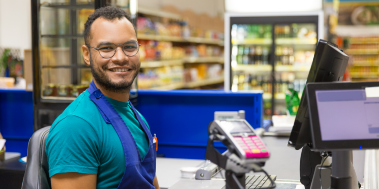 Operador de caixa sorridente em supermercado.