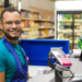 Operador de caixa sorridente em supermercado.