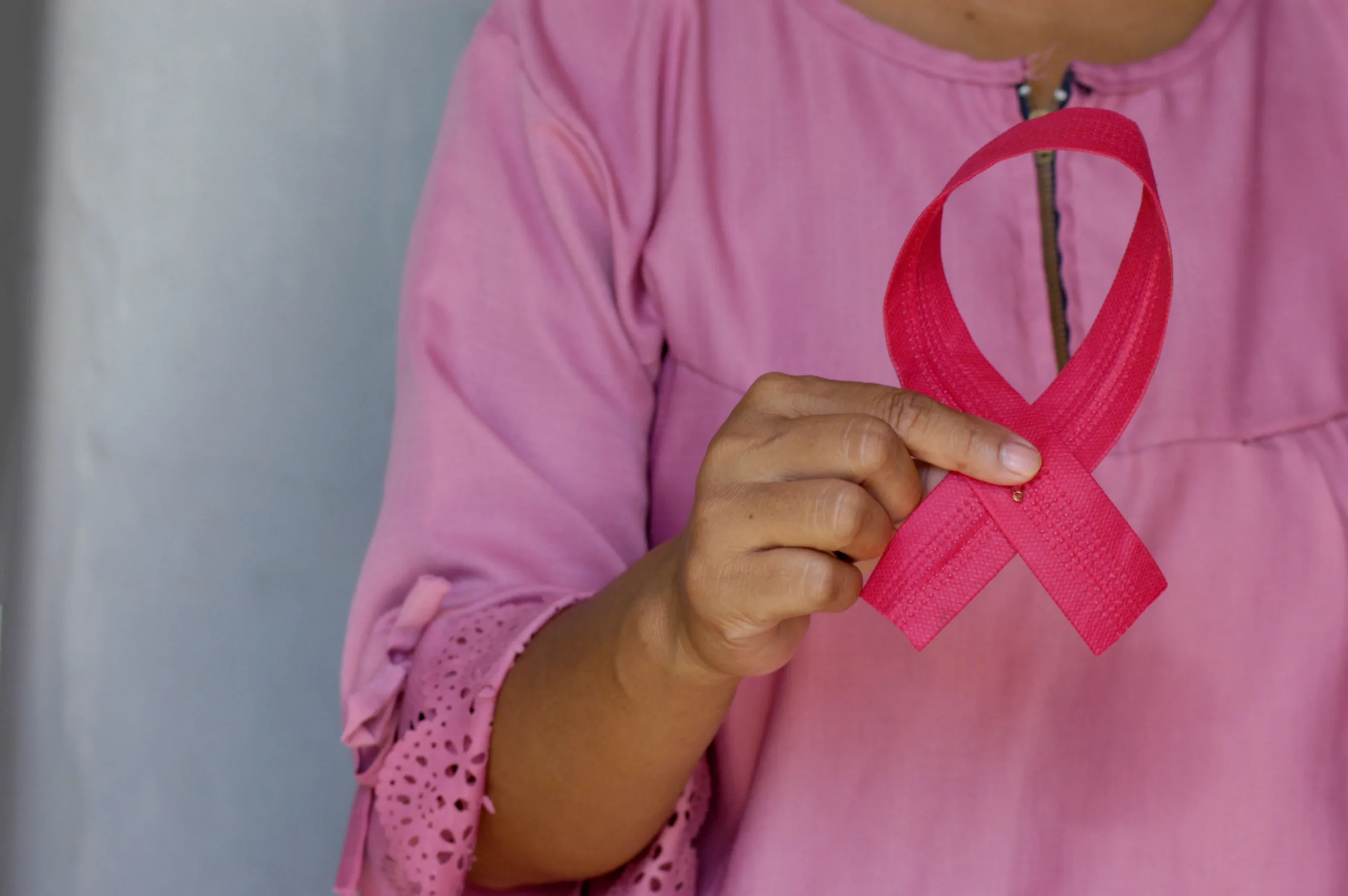Jovem segura fita rosa, símbolo da campanha Outubro Rosa