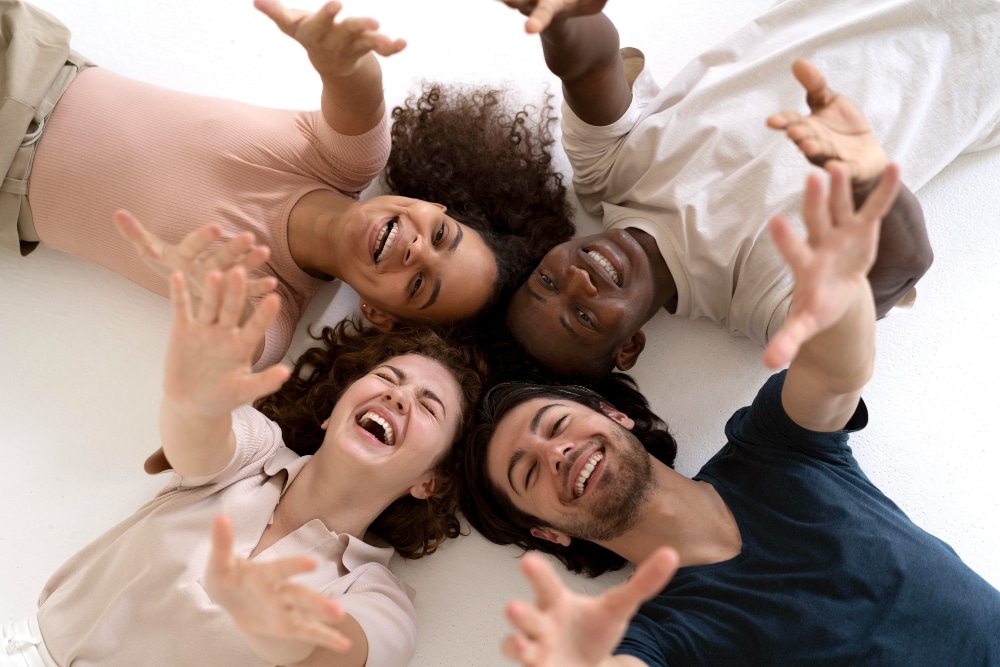 4 jovens extrovertidos deitados no chão sorrindo