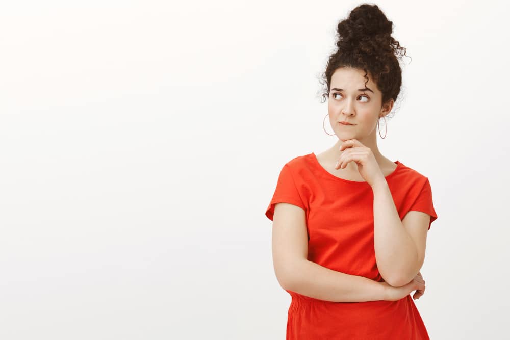 Mulher com blusa vermelha, coque e semblante de dúvida