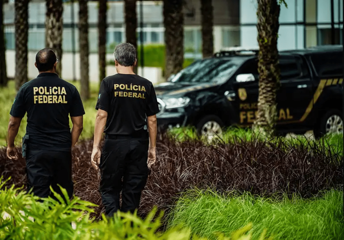 Agentes da PF ao ar livre, ao fundo veículo da instituição