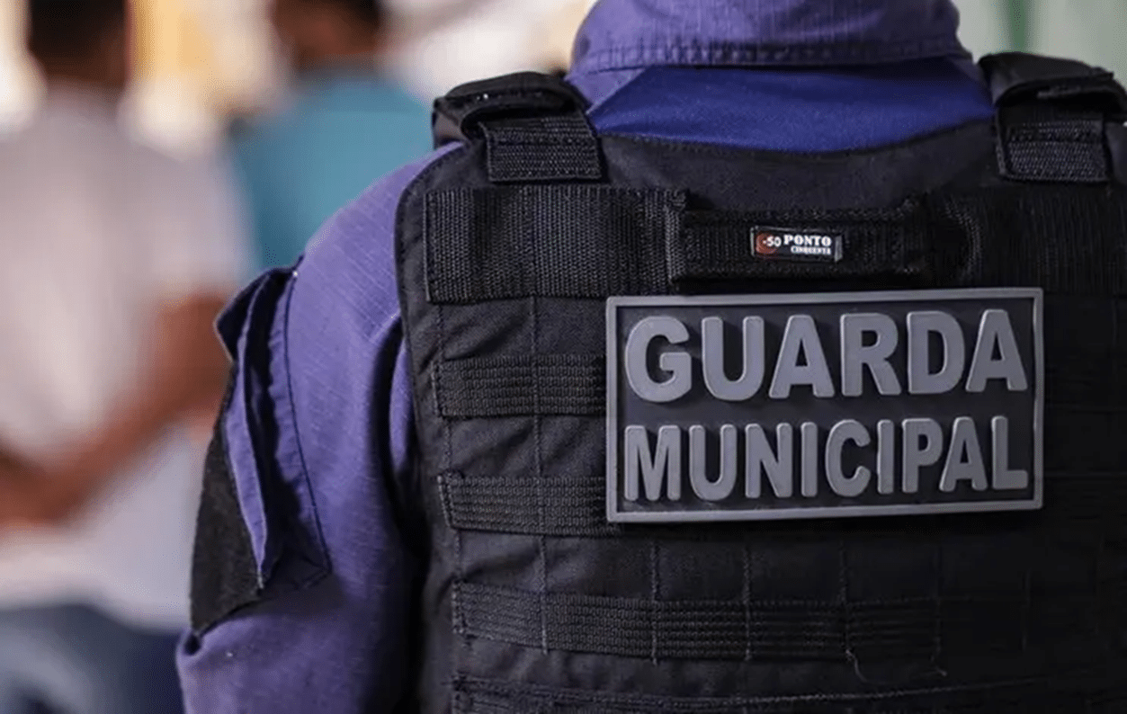 Guarda Municipal fardado em pé com logo da instituição virado de costas
