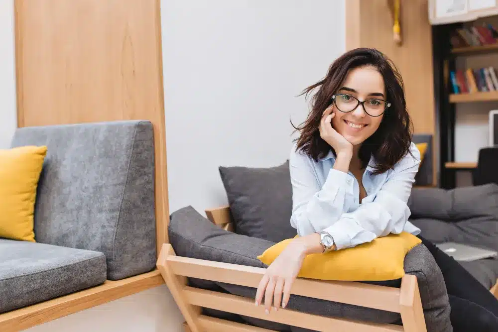 Mulher sorrindo em ambiente moderno e confortável, com expressão de confiança e inteligência