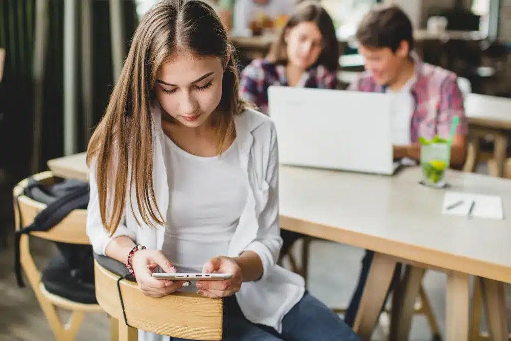 Relaxamento no Trabalho: O Impacto do Uso Excessivo de Smartphones Jovem da Geração Z usando smartphone no trabalho, representando o relaxamento durante o expediente