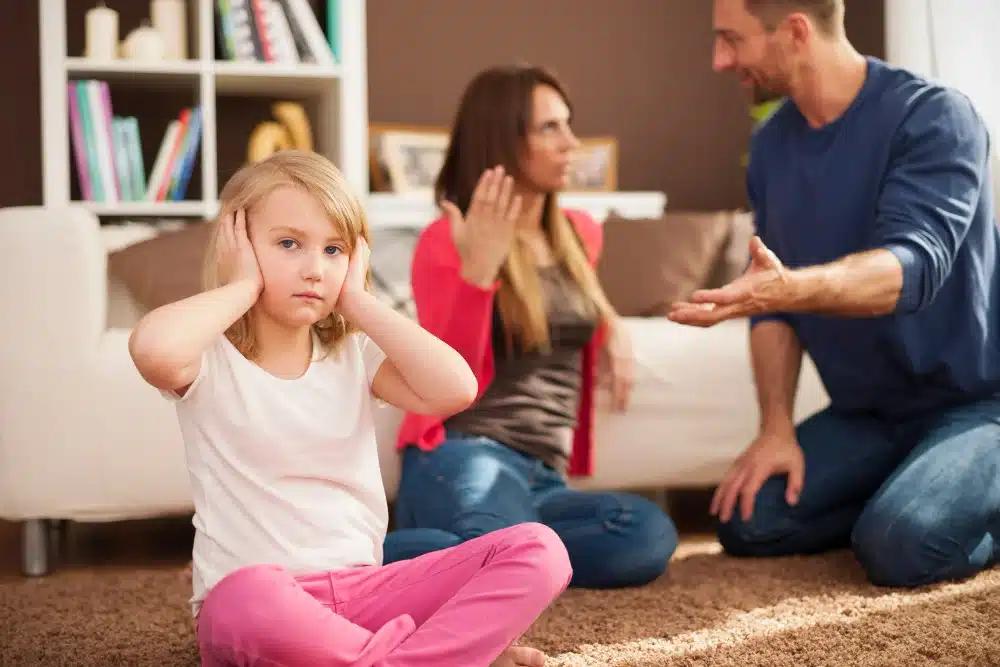 Criança cobrindo os ouvidos durante uma discussão entre os pais