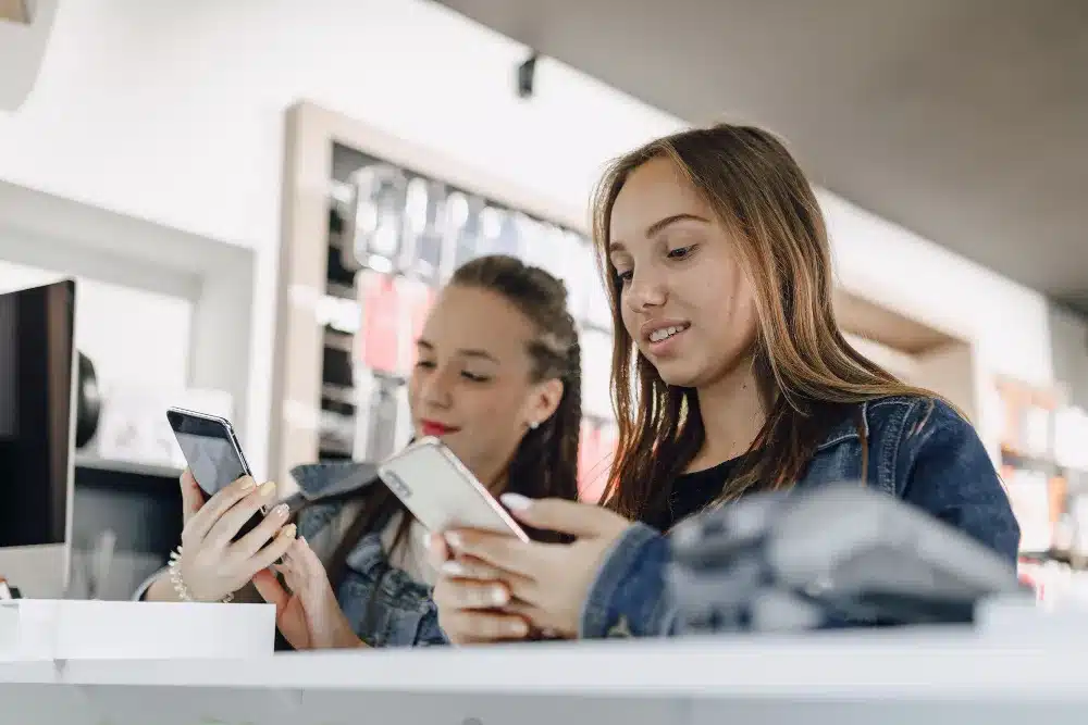 Jovens da Geração Z usando smartphones no ambiente de trabalho, representando o uso de tecnologia e foco no relaxamento.
