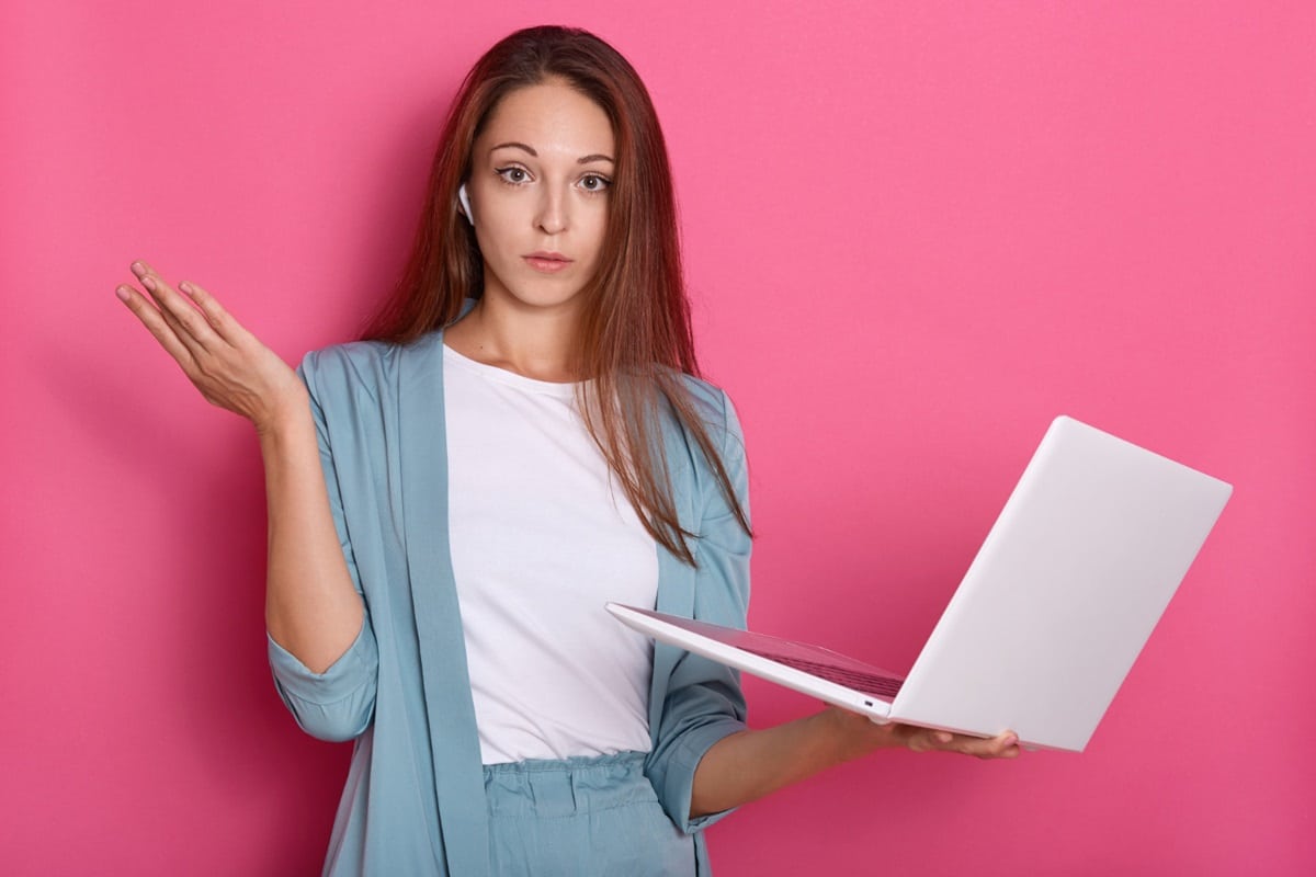 Mulher pensativa com laptop em mãos, representando dúvidas sobre abreviações formais em comunicações.