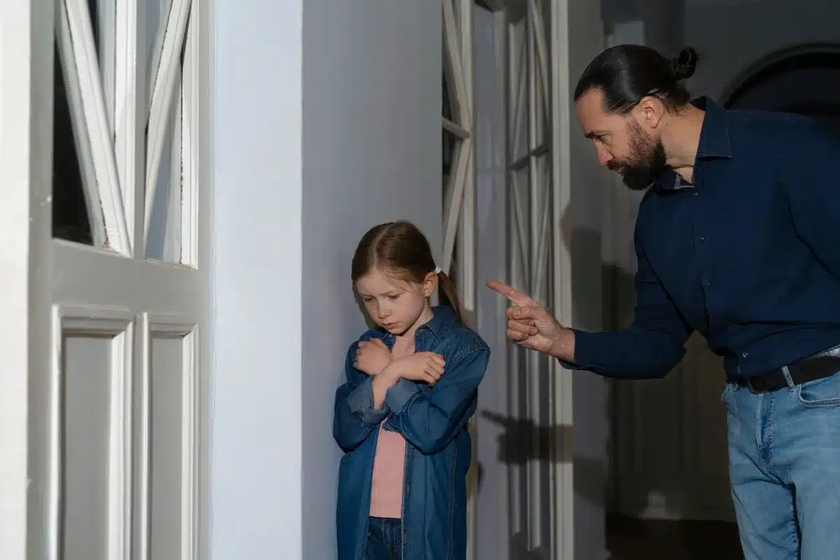 Pai repreendendo filha, ilustrando impacto de atitudes negativas na educação das crianças.