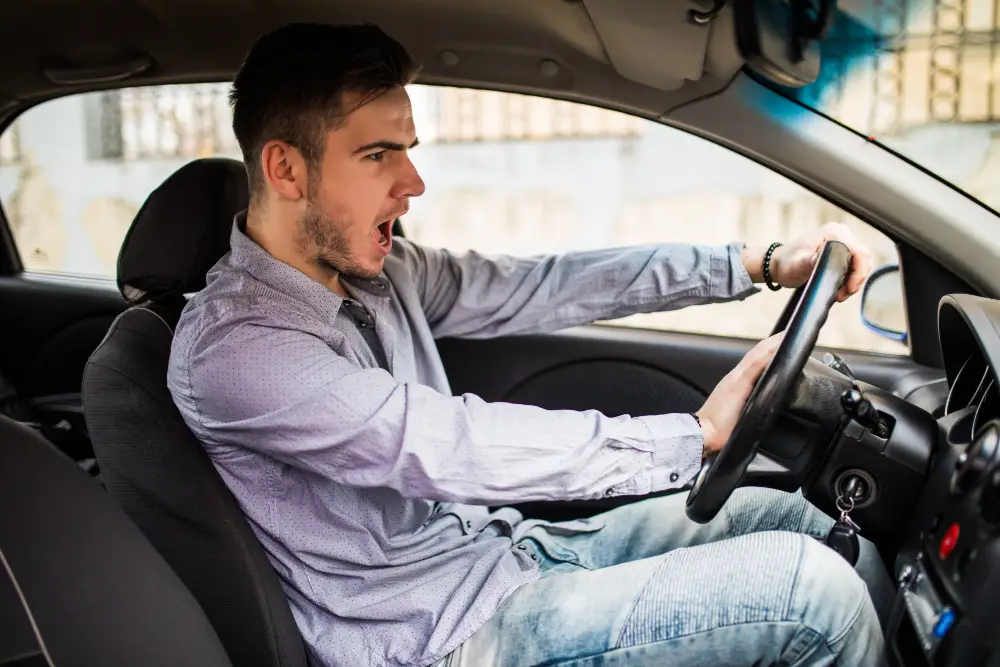 Direção perigosa e as emoções ao volante Motorista demonstrando raiva ao volante, ilustrando como emoções negativas podem afetar a segurança no trânsito.