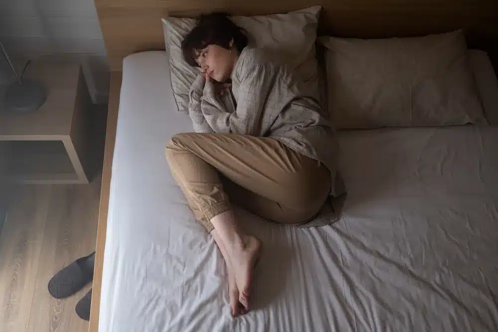 Raízes da desconfiança: como a falta de confiança se desenvolve Pessoa deitada na cama, simbolizando sentimentos de insegurança e falta de confiança.