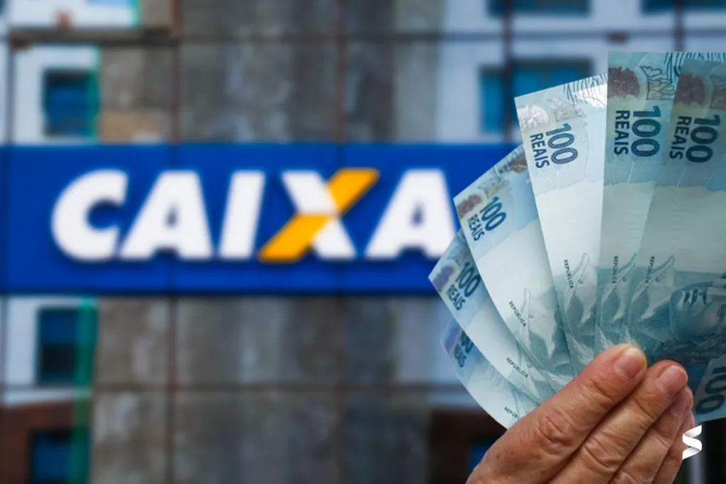 Mão segurando notas de 100 reais com fachada da Caixa Econômica Federal ao fundo.