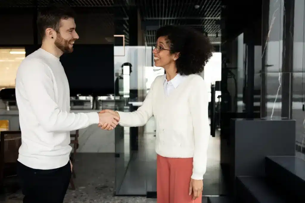 O poder do aperto de mão: Como causar uma boa primeira impressão. Duas pessoas cumprimentando-se com um aperto de mão, destacando o impacto nas primeiras impressões.