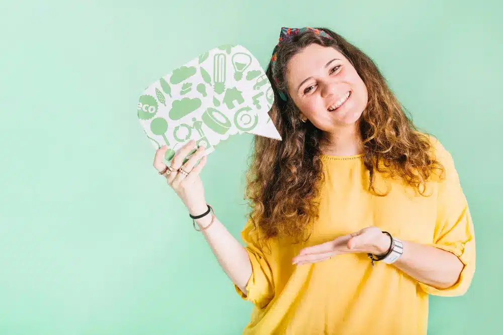Mulher sorrindo e segurando uma plaquinha, simbolizando a inteligência emocional e a comunicação.