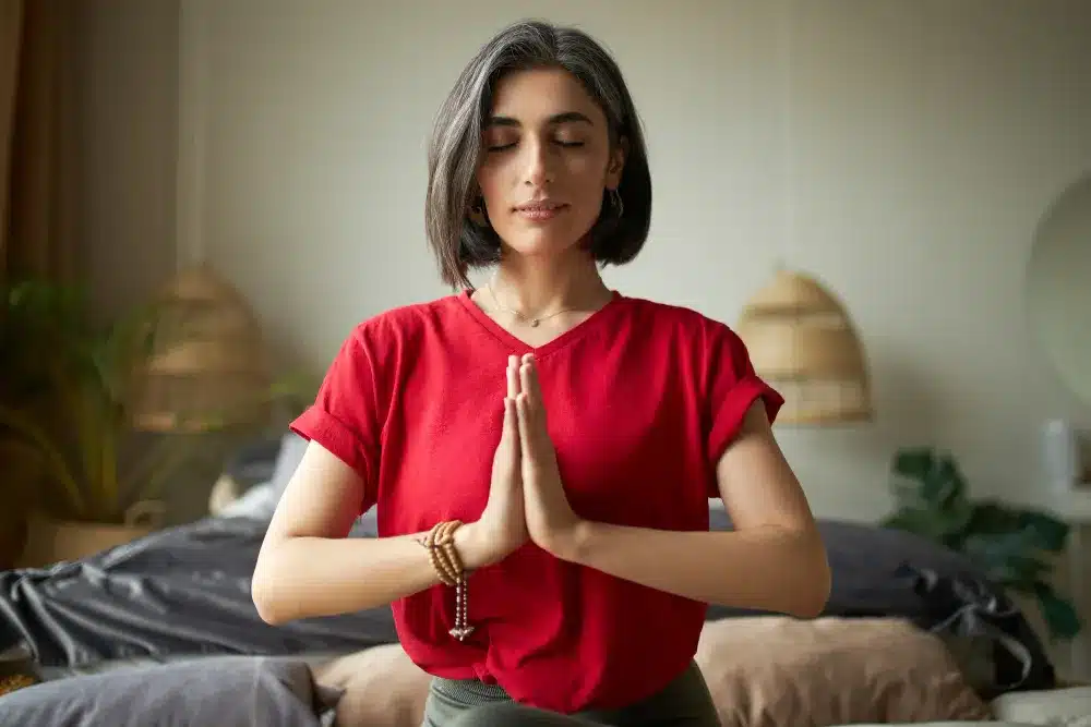 Mindfulness como ferramenta para transformação pessoal. Mulher em meditação com as mãos unidas, praticando mindfulness e autorreflexão.