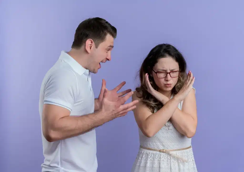 Rejeição a conflitos em relações interpessoais Mulher com expressão de incômodo e braços cruzados em "X", rejeitando uma discussão com um homem exaltado