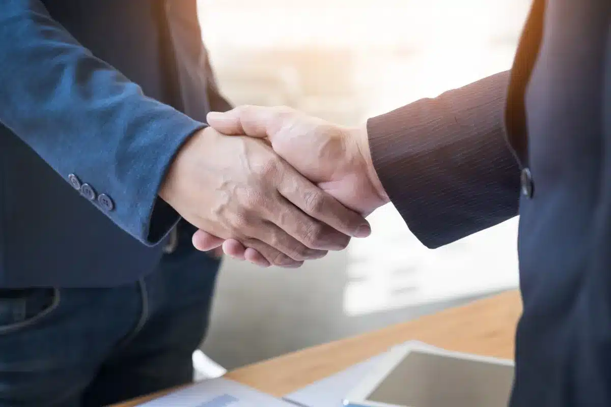 Aperto de mão firme entre duas pessoas, simbolizando confiança e profissionalismo.