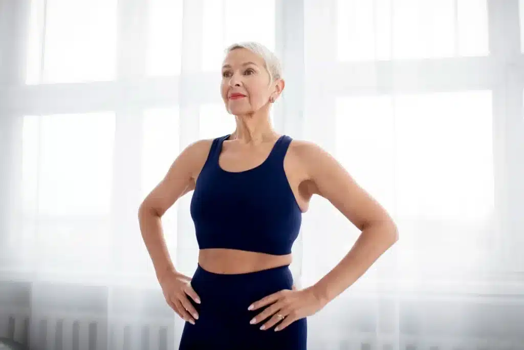 Frase 3: "Você ainda tem muita energia" Mulher madura e confiante vestindo roupa de ginástica, exibindo vitalidade e força.