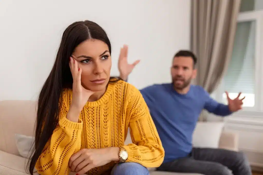 Casal discutindo em diferentes fases da vida Mulher exausta, ouvindo um homem em discussão, refletindo uma fase de desconexão e diferenças de perspectivas em um relacionamento.