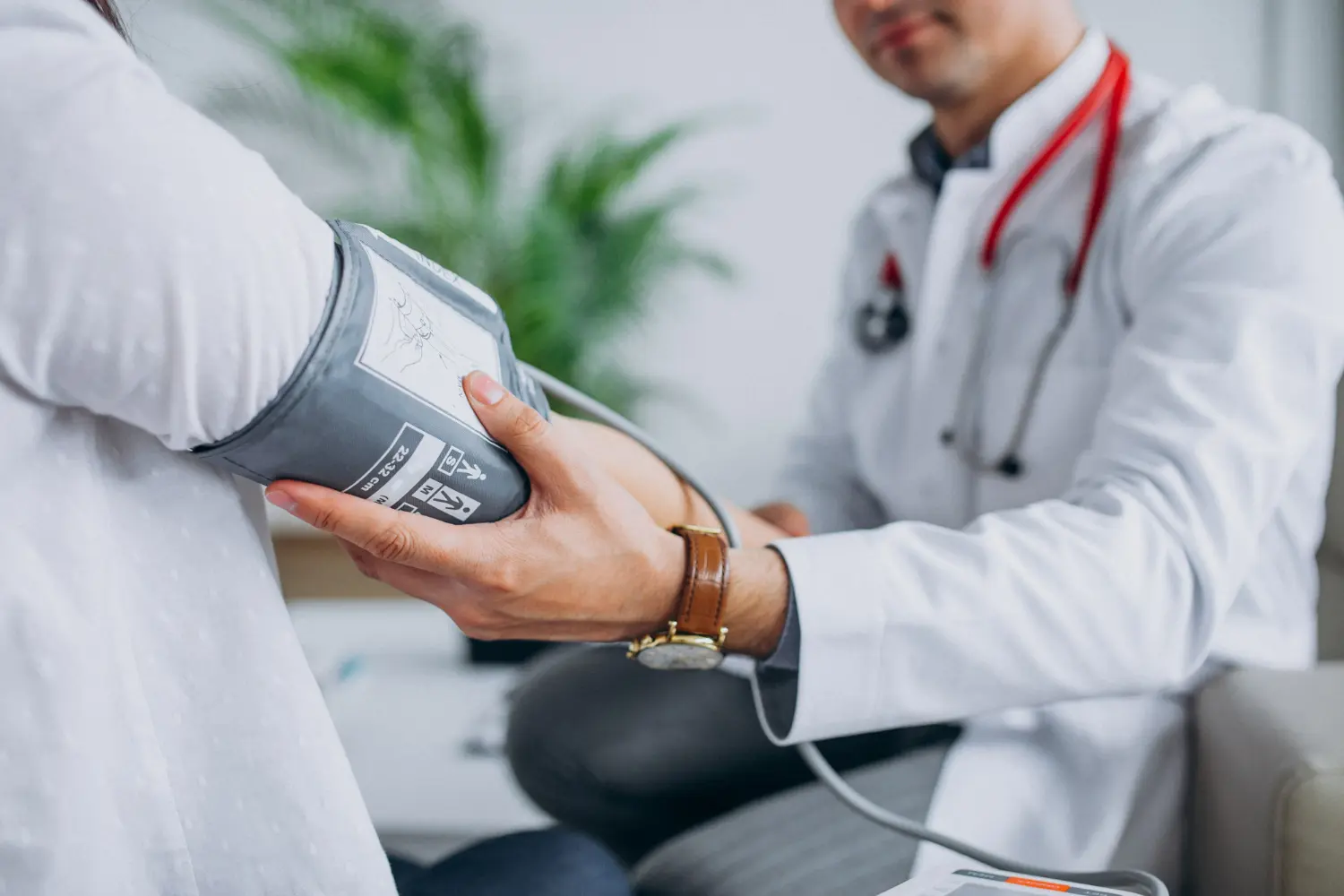 Médico medindo a pressão arterial de paciente em consultório médico. Médico realizando medição de pressão arterial em paciente, ilustrando a profissão de saúde em Portugal.