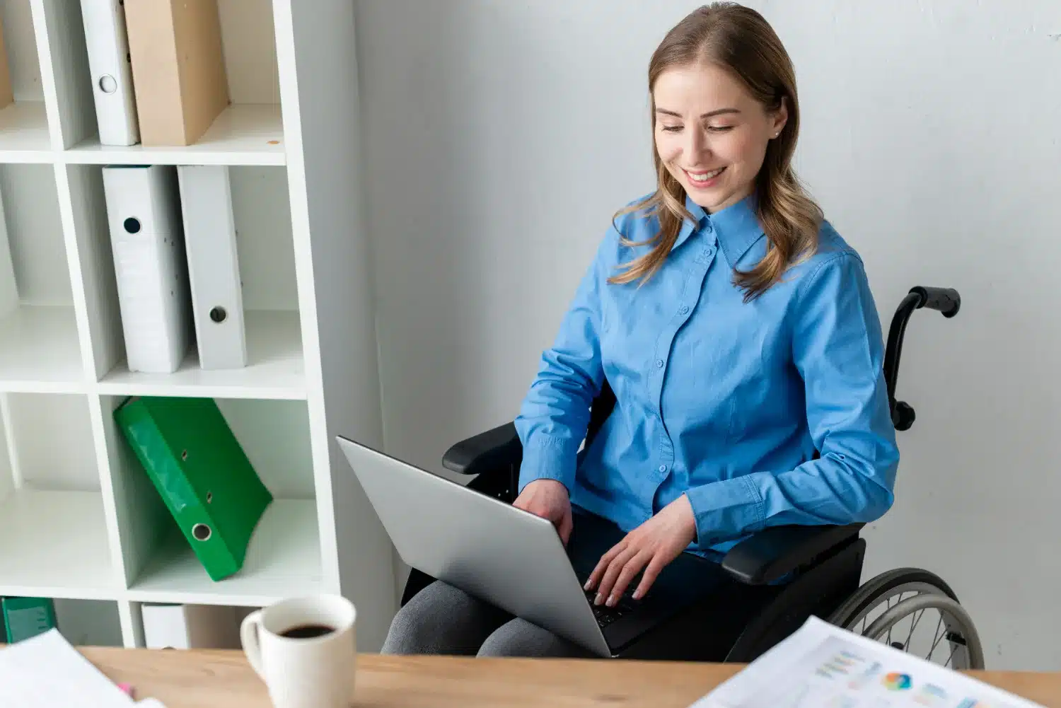 Comprovação de deficiência para elegibilidade Mulher em cadeira de rodas trabalhando em um laptop.