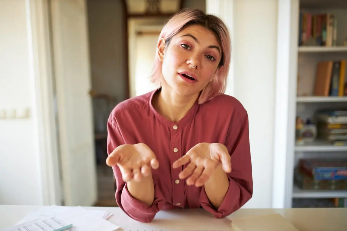 Quando as desculpas viram hábito: um sinal de comportamento folgado Mulher com expressão de indiferença e mãos levantadas como quem justifica ou dá desculpas.