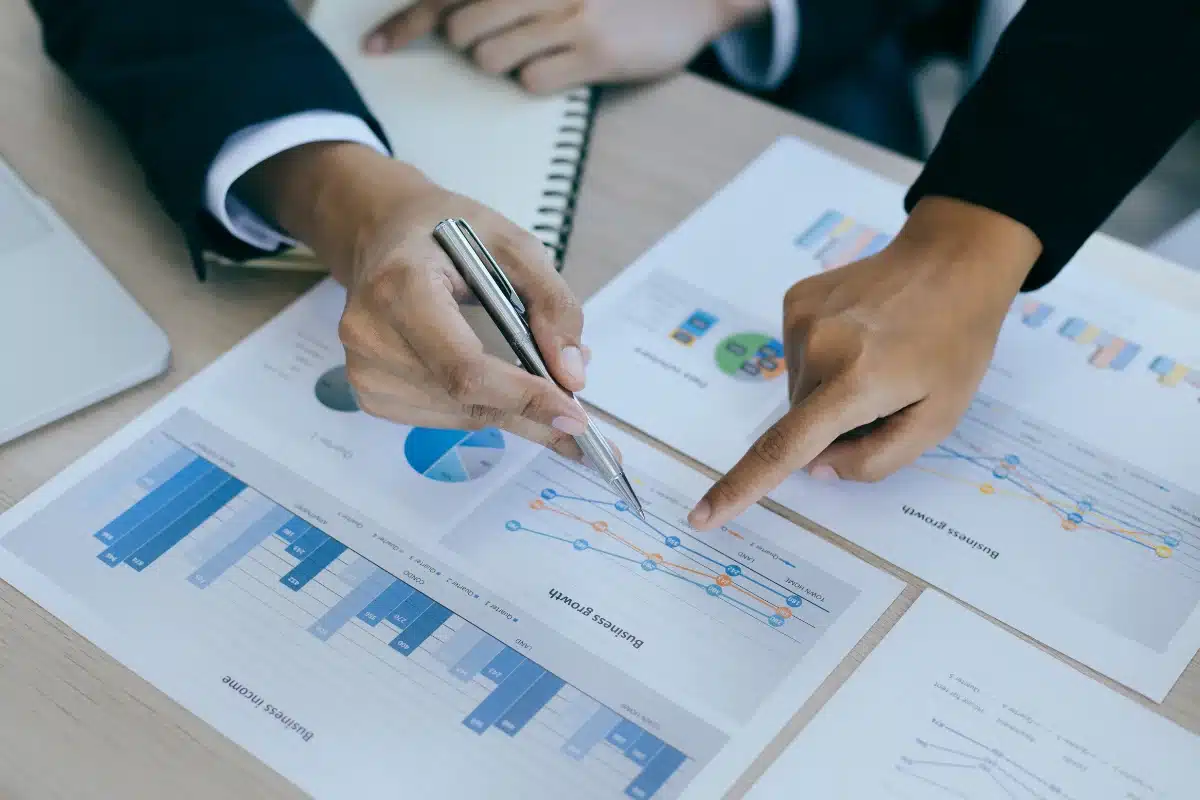 Análise das profissões em alta Pessoa analisando gráficos de desempenho de negócios, apontando para uma linha de crescimento em um gráfico impresso.