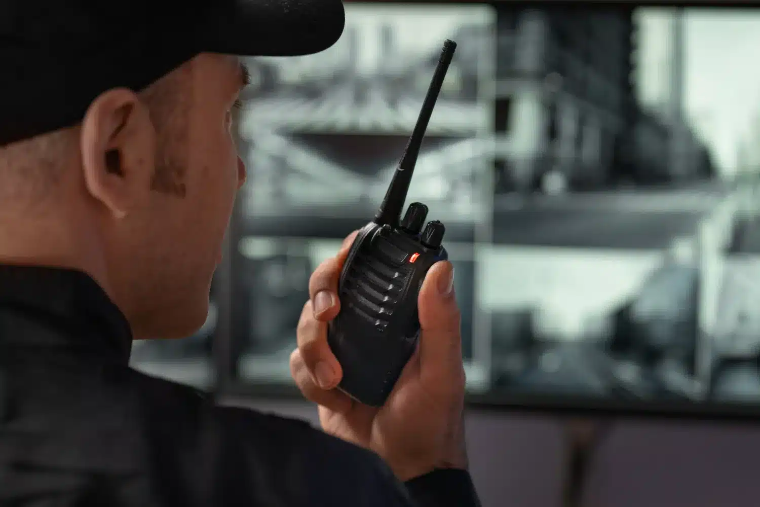 Necessidade de atualização: vigilantes e novas tecnologias de segurança Vigilante utilizando rádio comunicador enquanto monitora câmeras de segurança, destacando a importância da atualização tecnológica.