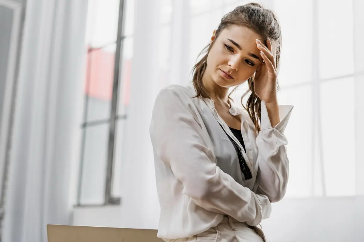 Reflexões e impactos da autocrítica no dia a dia Mulher pensativa apoiando a mão na cabeça, expressando preocupação ou reflexão.