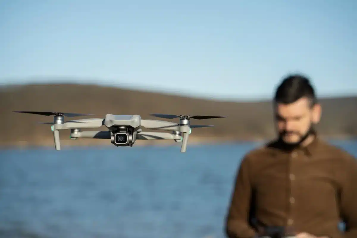 Engenheiro de Drones: Uma profissão inovadora Drone voando sobre uma paisagem com um profissional no fundo, representando a profissão de engenheiro de drones.