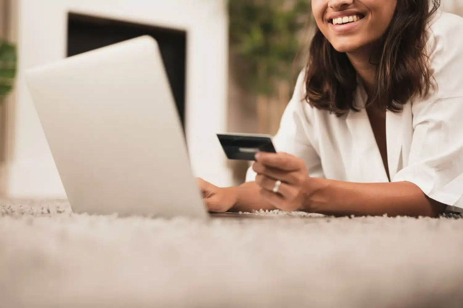 Compras online com cartão de crédito Pessoa sorrindo enquanto faz compras online com cartão de crédito e laptop.