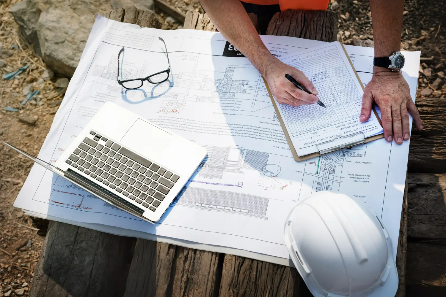 Engenheiro trabalhando em projeto de infraestrutura Profissional de engenharia analisando planos de construção com laptop e documentos sobre a mesa.