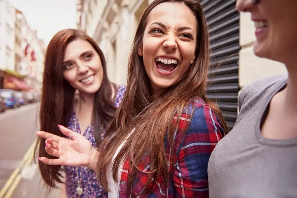 O que influencia as crises de riso? Descubra os fatores Grupo de amigas rindo e se divertindo em um ambiente urbano.