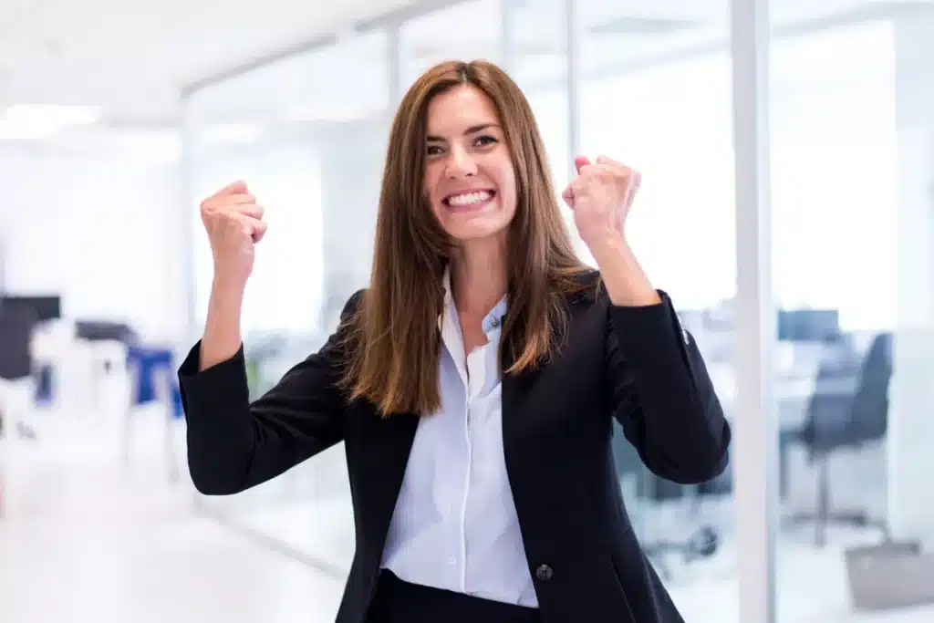 Valorização da Mentalidade de Crescimento nas Empresas Mulher comemorando uma conquista no escritório, representando a importância de uma mentalidade de crescimento nas empresas.