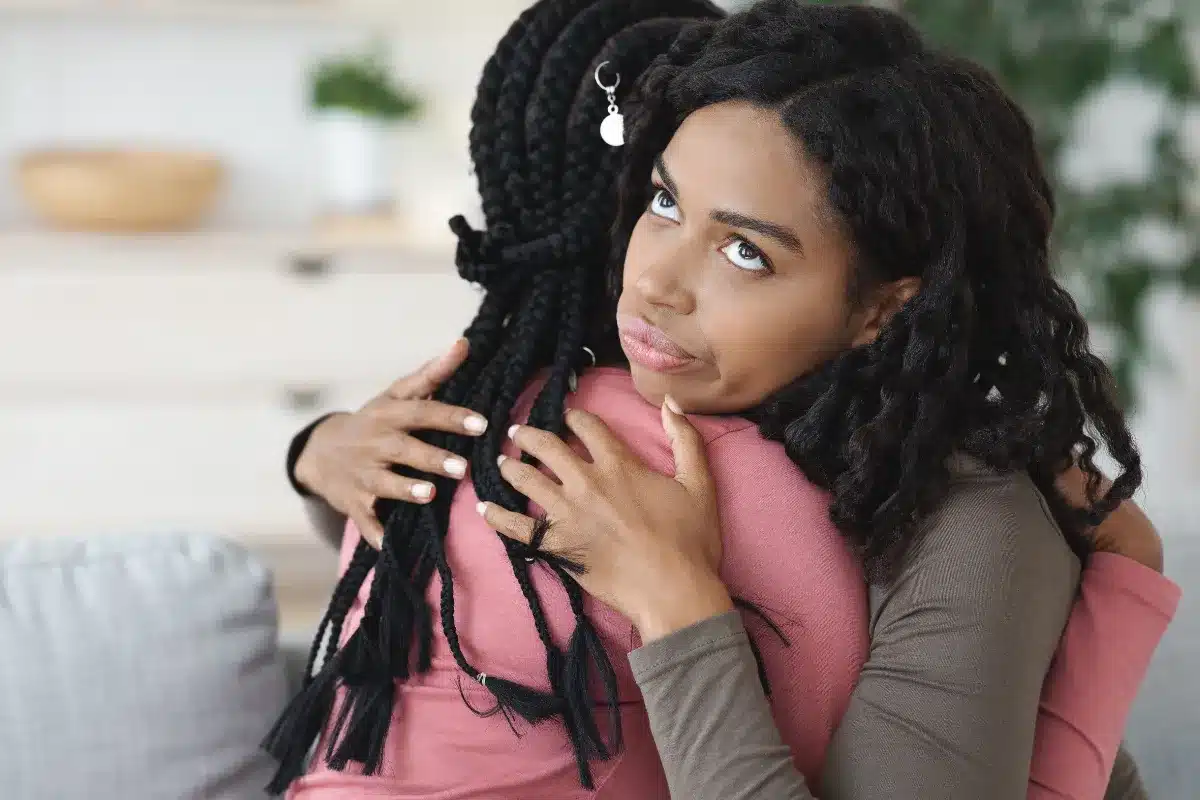 Abraço entre amigas com expressão desconfortável. Mulher com expressão desconfortável durante um abraço, indicando uma sensação de falsidade.