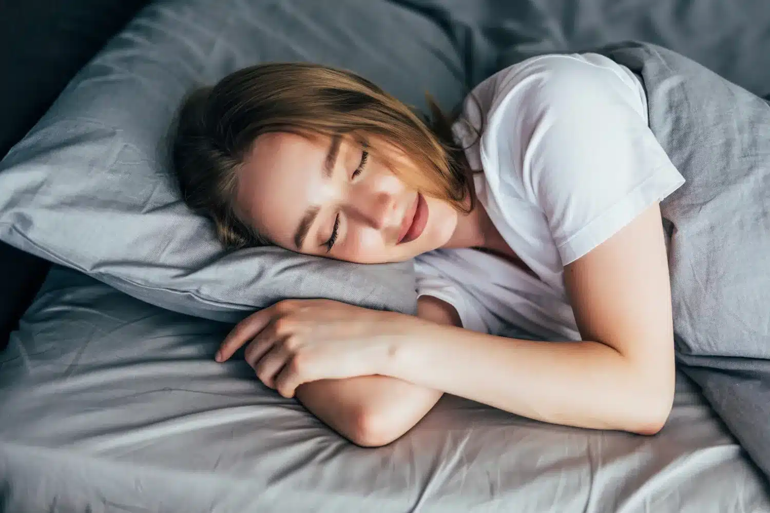 Mulher dormindo tranquilamente em uma cama cinza, representando o processo de lembrança dos sonhos