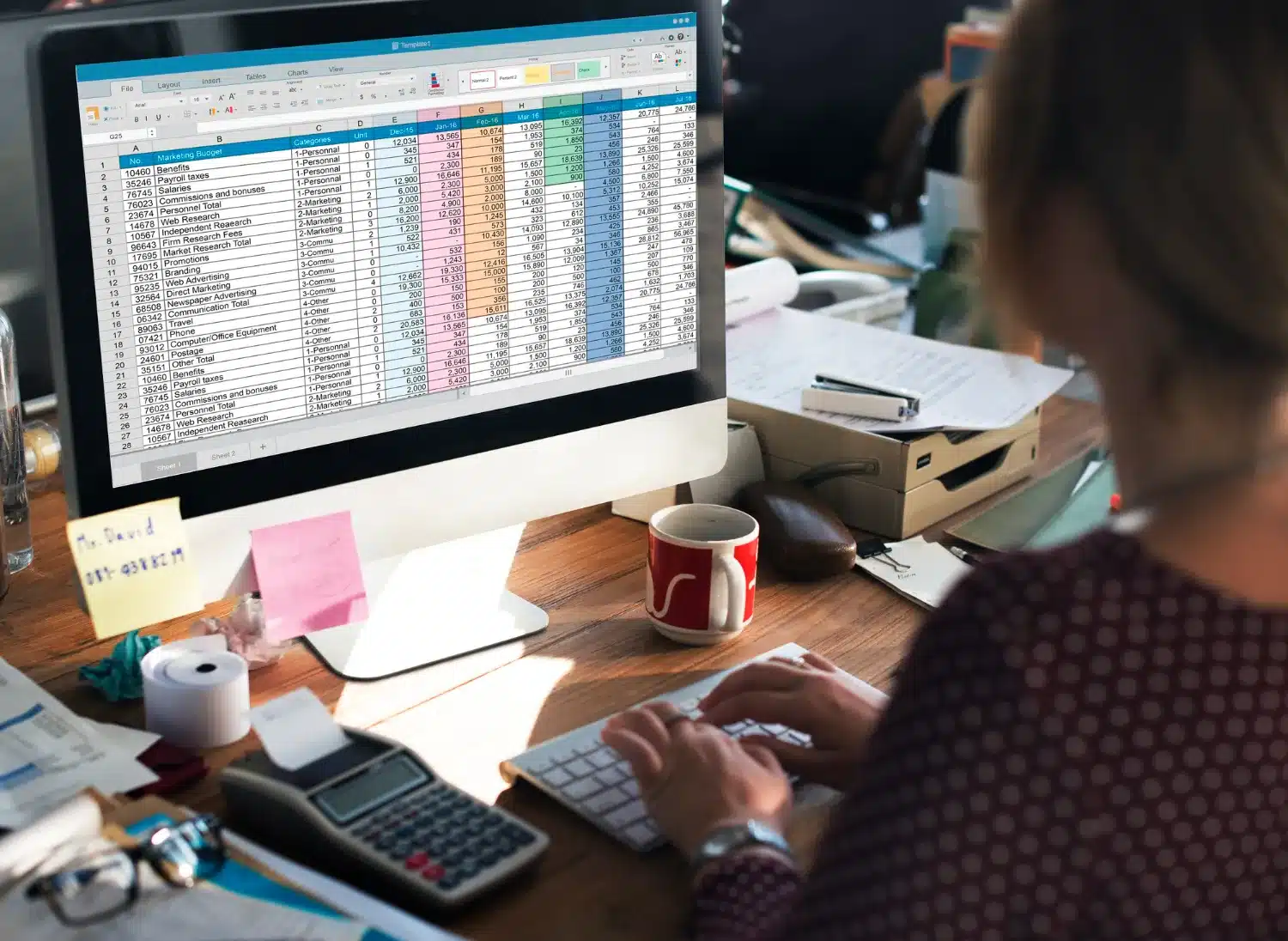 Pessoa trabalhando em uma planilha de Excel no computador, com cálculos financeiros visíveis