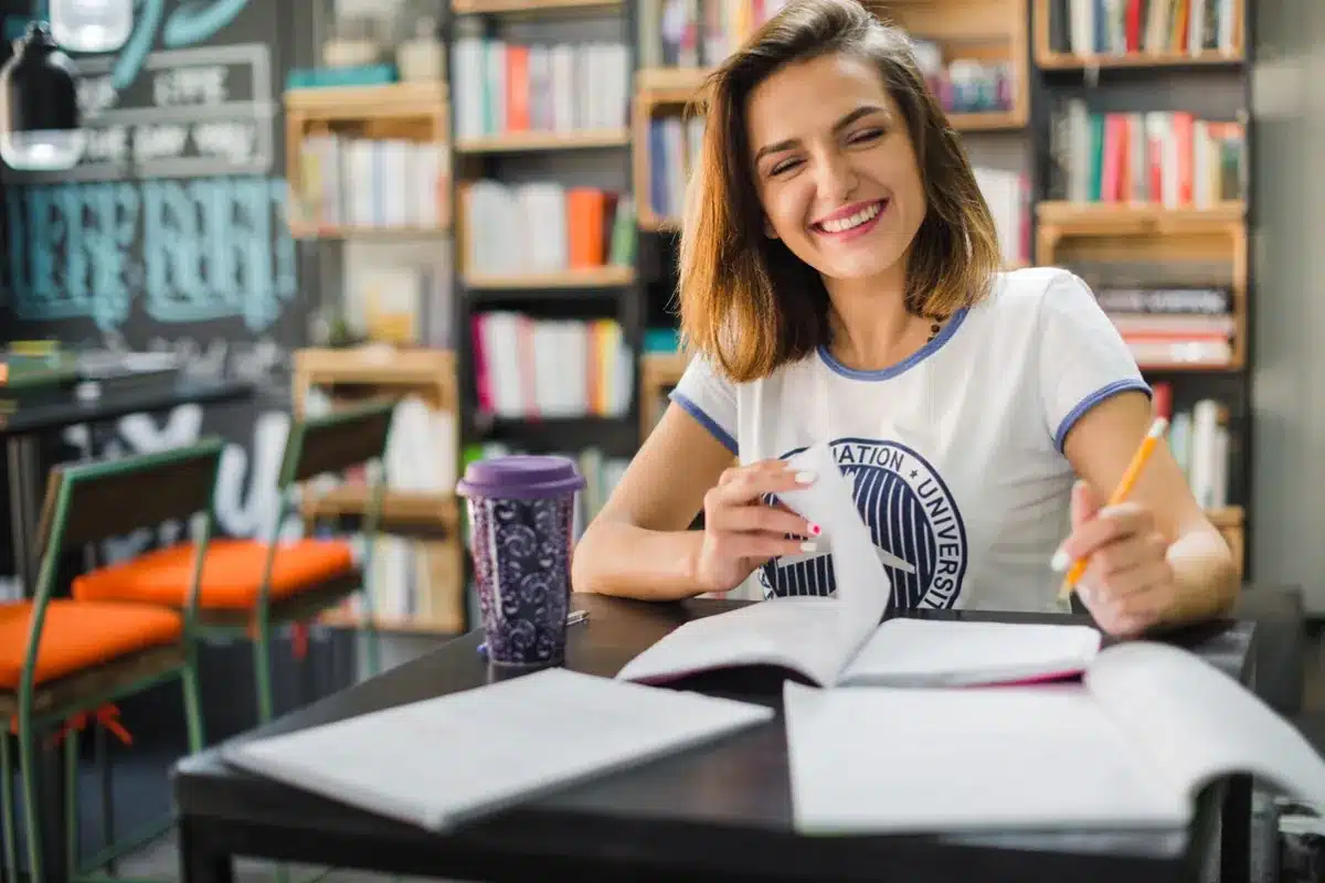 Estudante sorrindo enquanto estuda, simbolizando o tema de matrículas e bolsas do Prouni, refletindo as mudanças nas matrículas universitárias ao longo dos anos.