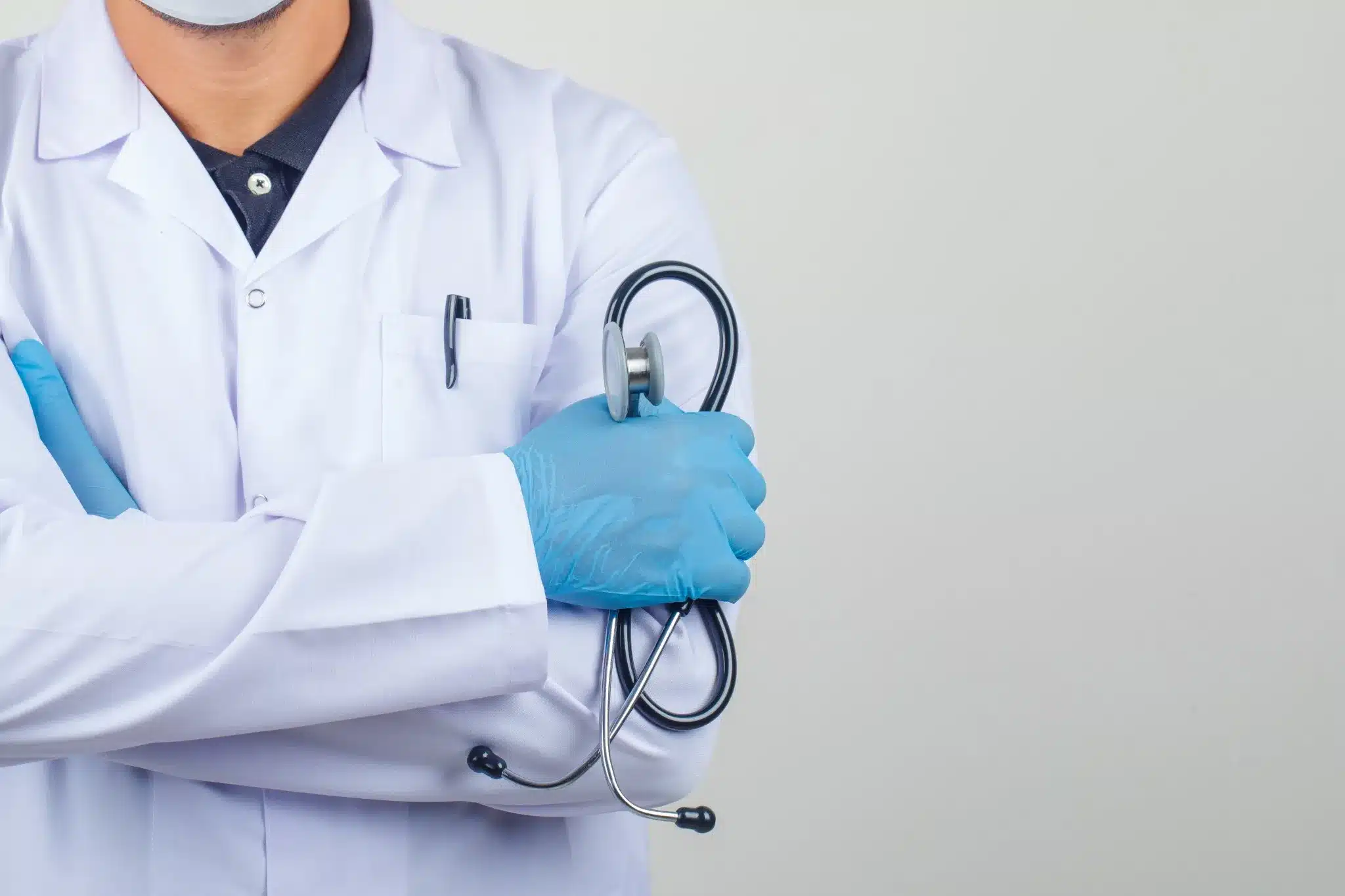 Processo Seletivo para profissionais de saúde Médico de jaleco segurando um estetoscópio com luvas azuis.