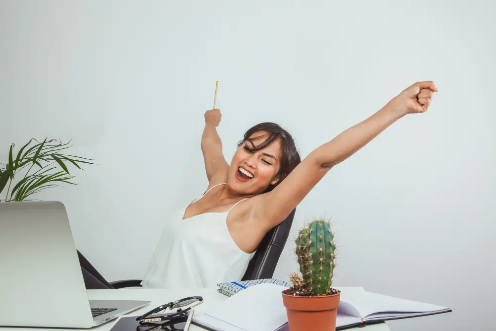 Motivação e busca pela excelência pessoal e profissional Pessoa levantando os braços com expressão de felicidade, simbolizando a motivação interna e busca por excelência no trabalho.