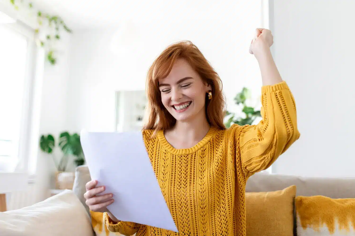 Mulher sorrindo e comemorando ao ler uma carta, simbolizando a satisfação com a redução nas contas de energia.