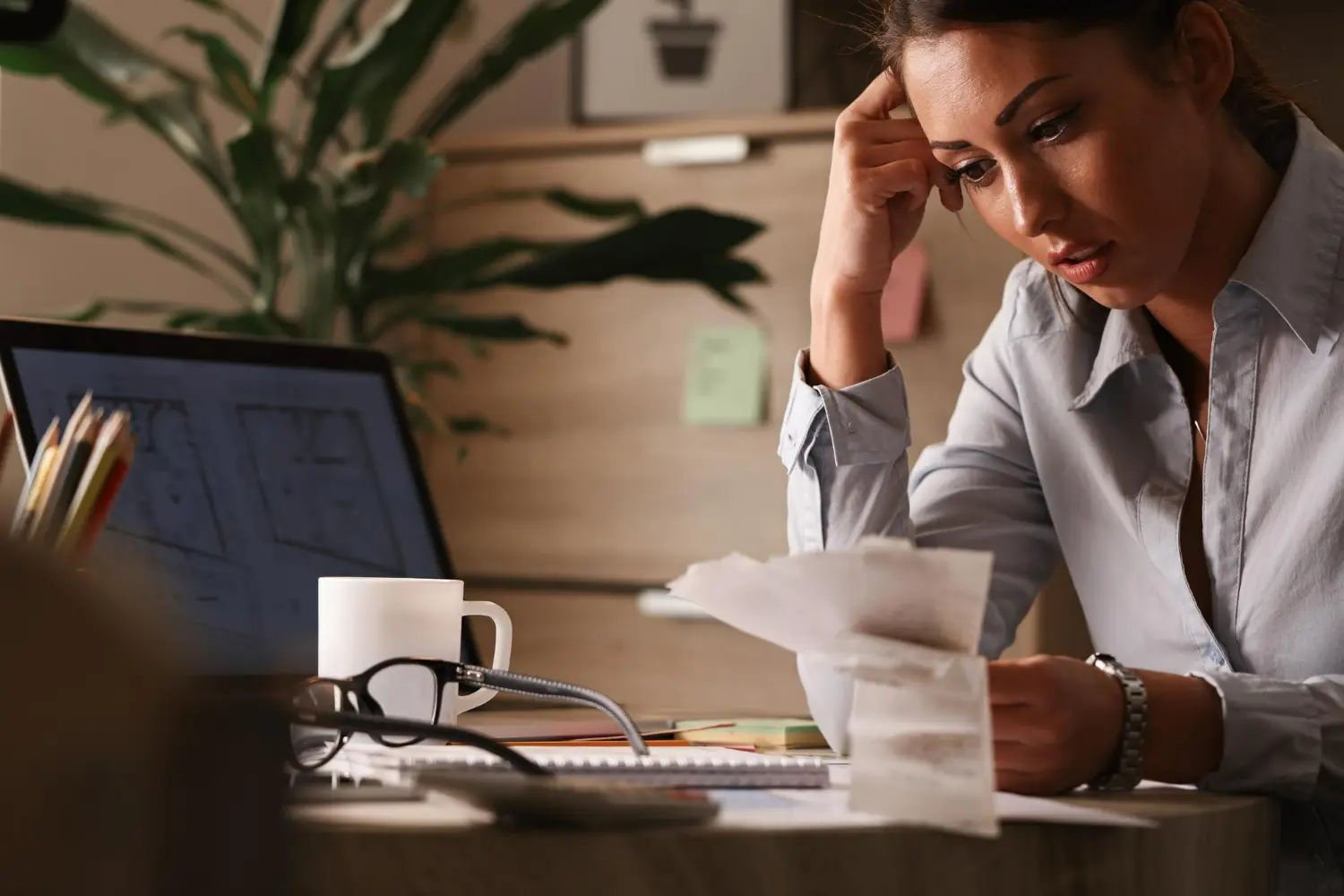 Mulher analisando contas e demonstrando preocupação com descontrole financeiro Mulher preocupada com documentos financeiros e notas, representando o descontrole financeiro.