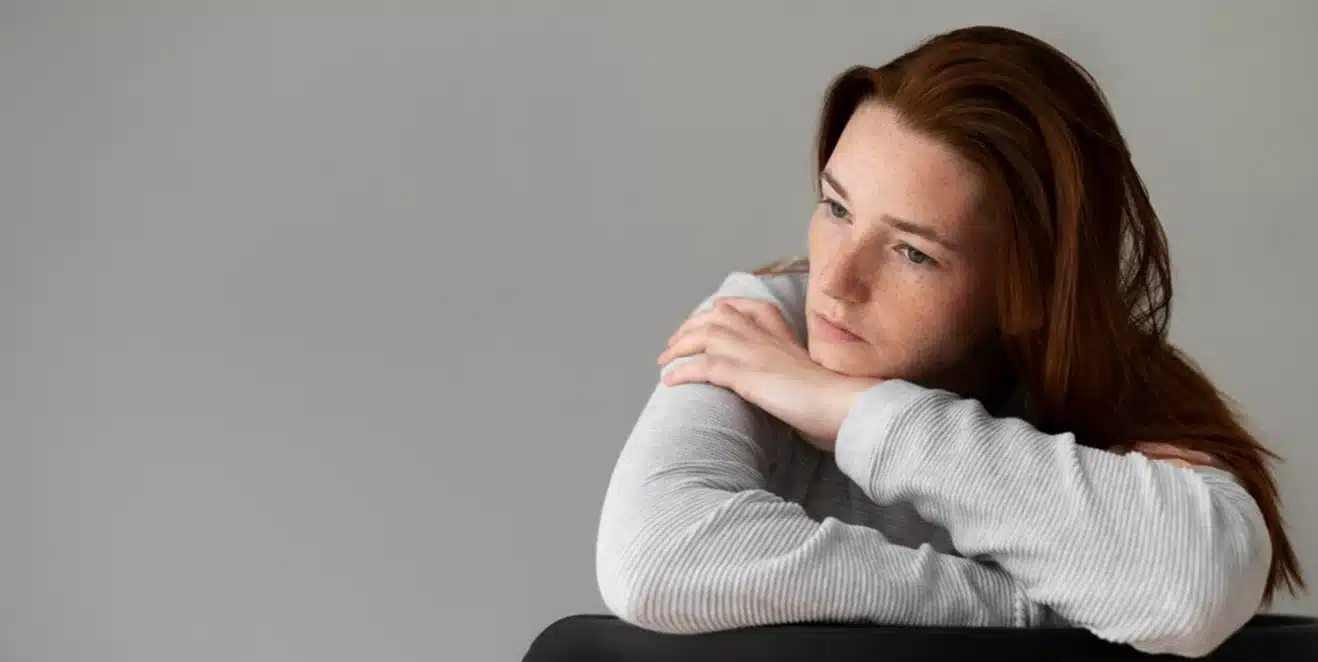 Reflexão sobre baixa autoestima: como a necessidade de aceitação afeta o bem-estar Mulher pensativa refletindo sobre sua baixa autoestima e a busca por validação externa.