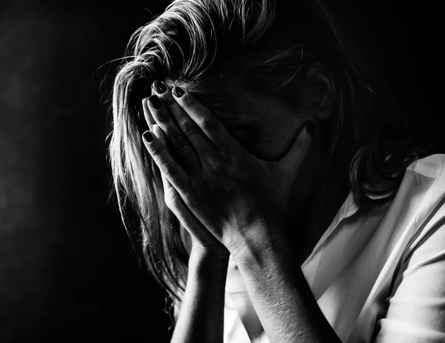 Pessoa com expressão de angústia, cobrindo o rosto com as mãos, simbolizando o estado emocional de pessimismo.